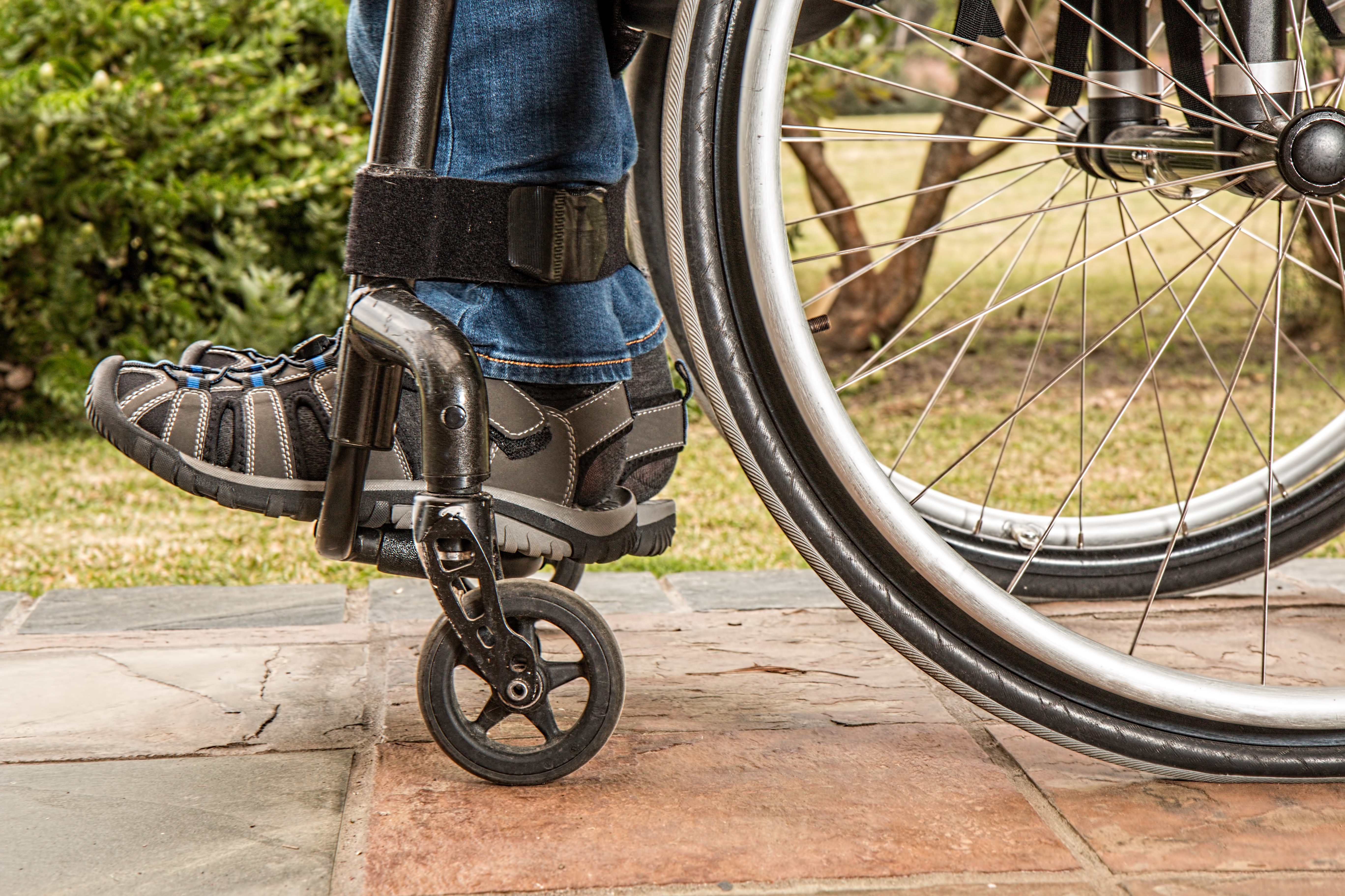 Räder eines Rollstuhls auf unebenem Belag